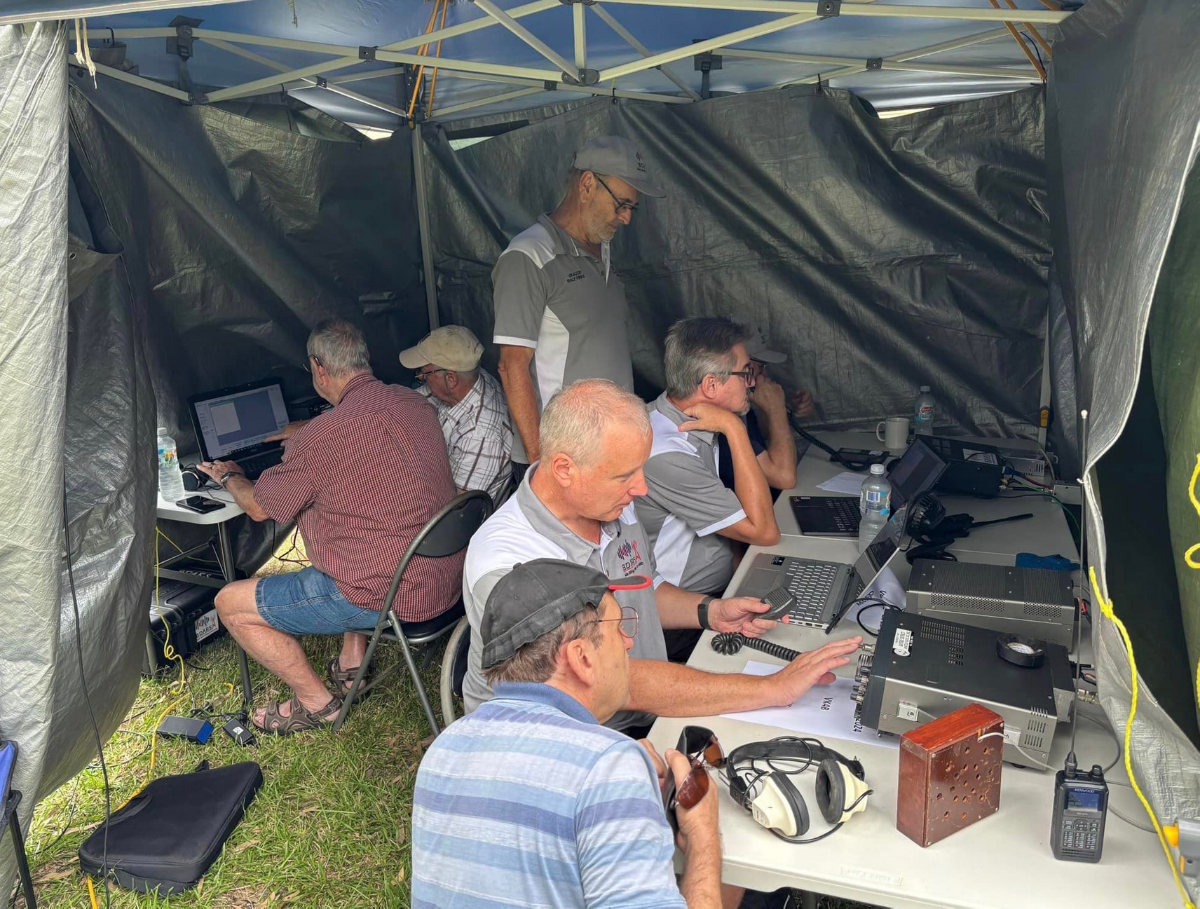 Several members huddled under gazebo operating radios